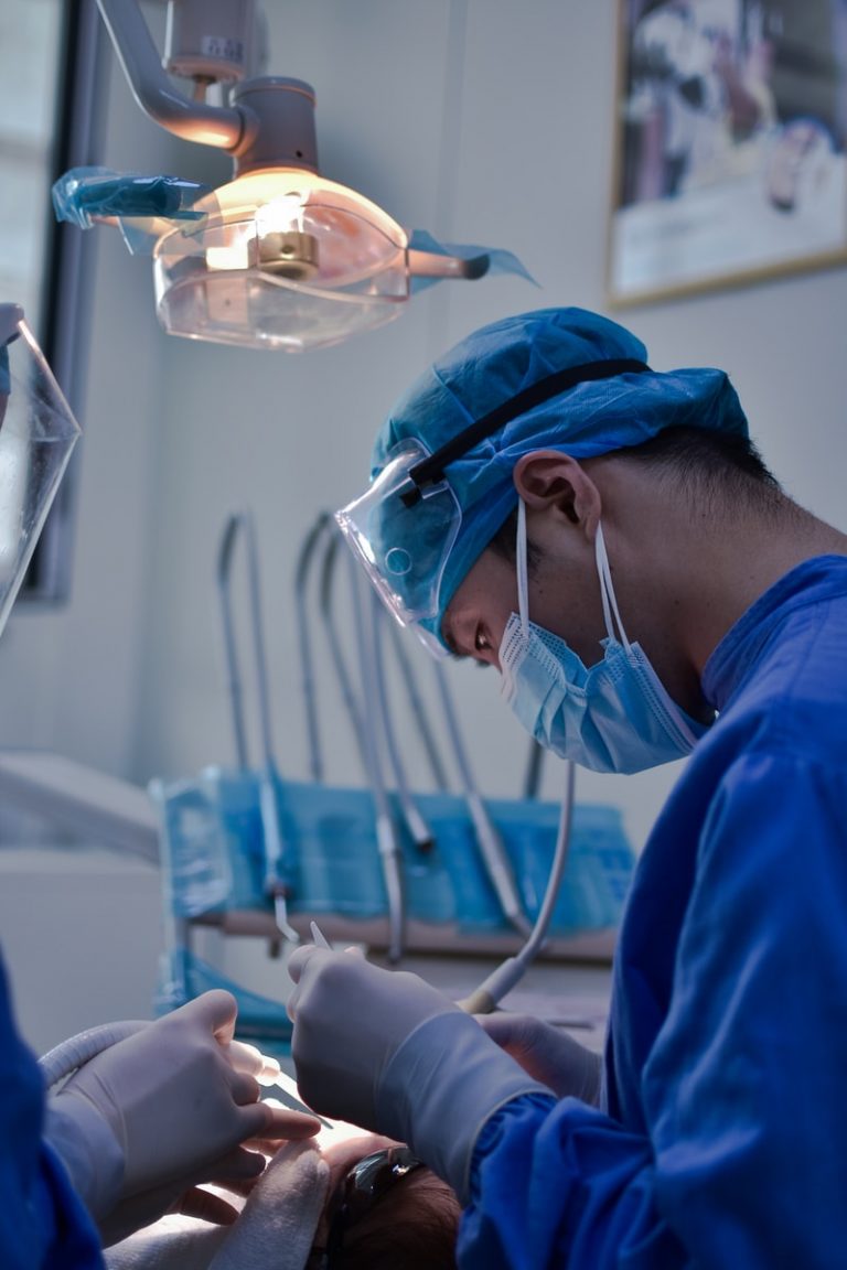 person in blue scrub suit holding clear glass cup